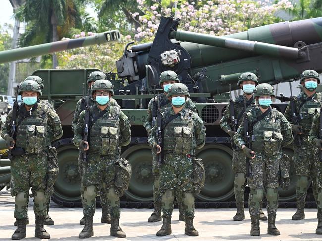 Soldiers wearing face masks amid the COVID-19 coronavirus pandemic stand in formation in front of a US-made M110A2 self-propelled howitzer during Taiwan President Tsai Ing-wen's visit to a military base in Tainan, southern Taiwan, on April 9, 2020. - Taiwan currently has just 375 confirmed Covid-19 patients and five deaths despite its close proximity and trade links with China where the pandemic began, but the island and its 23 million inhabitants remain locked out of the World Health Organisation (WHO) and other international bodies after Beijing ramped up its campaign to diplomatically isolate Taiwan and pressure it economically and militarily. (Photo by Sam Yeh / AFP)