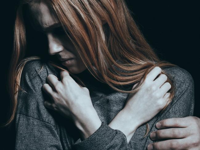 Fearful rape victim, man holding her arm, black background