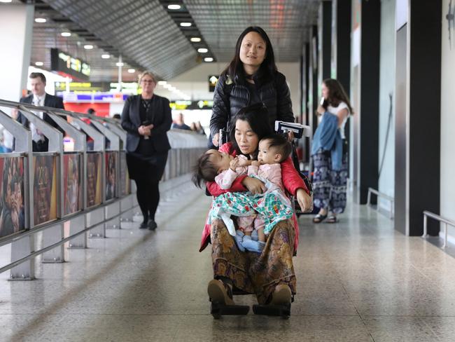 Travelling nurse Tshewang Choden pushes mum Bhumchu Zangmo in a wheelchair as she holds Nima and Dawa at Melbourne airport after the flight from Bhutan and Bangkok. Picture: Alex Coppel