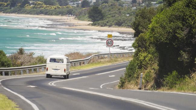 Lorne, Australia - January 3, 2018: A Volkswagen Kombi (or Transporter) van driving down Great Ocean Road, with Lorne Beach in the background.