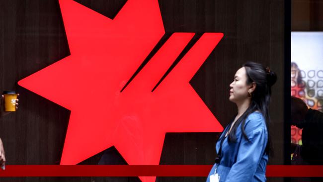 Pedestrians walk past the logo of National Australia Bank, on display outside a branch in central Sydney on November 7, 2024. National Australia Bank released its full-year financial results for 2024 on November 7. (Photo by DAVID GRAY / AFP)