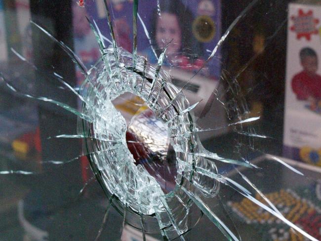 A bullet hole in a shop window at the murder scene.