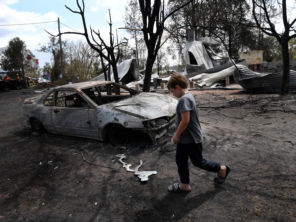 A boy walks past a home burned down in bushfires during Australia’s “Black Summer” of 2019 . (AAP Image/Dan Peled) NO ARCHIVING