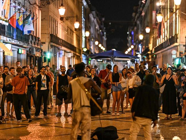 People enjoy music played by street artists at Rua Augusta after the lights were restored following a massive power cut affecting the entire Iberian peninsula and the south of France, in Lisbon on April 28, 2025. Spanish Prime Minister Pedro Sanchez said today authorities were not ruling out any  cause for the widespread blackout across the Iberian pensisula. 