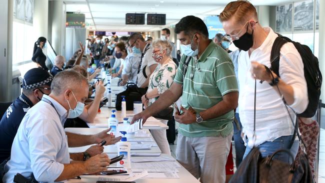 People arriving from Sydney are greeted by health authorities at Brisbane Airport on Sunday. Picture: Steve Pohlner