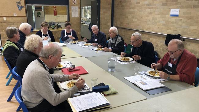 Participants, and their two volunteer instructors, in a Men's Kitchen Northern Beaches cooking skills session enjoy the lunch they prepared at the Forestville Community Hall in May this year. The classes are set to expand across the city. Picture: Jim O'Rourke