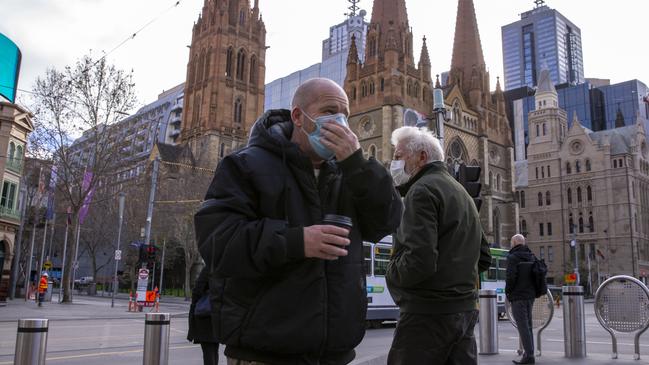 The cover-up begins in Melbourne, with people at the junction of Flinders and Swanston streets wearing face masks on Thursday. Picture: Wayne Taylor