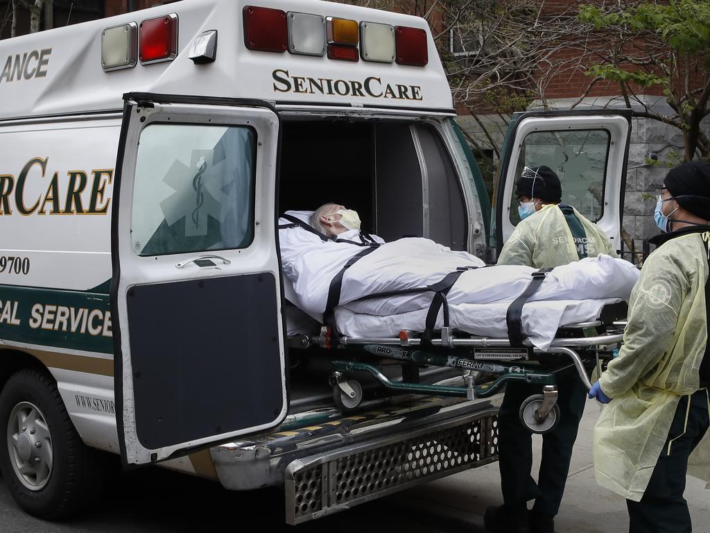 A patient is loaded into an ambulance by emergency medical workers in Brooklyn. Hospitals, nursing homes, and now funeral homes are seeing bodies piling up. Picture: AP Photo