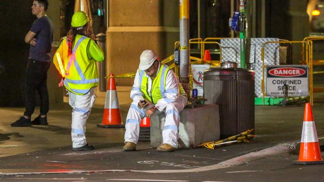 A worker checks his phone at the corner of Market St and George St. Picture: Simon Bullard