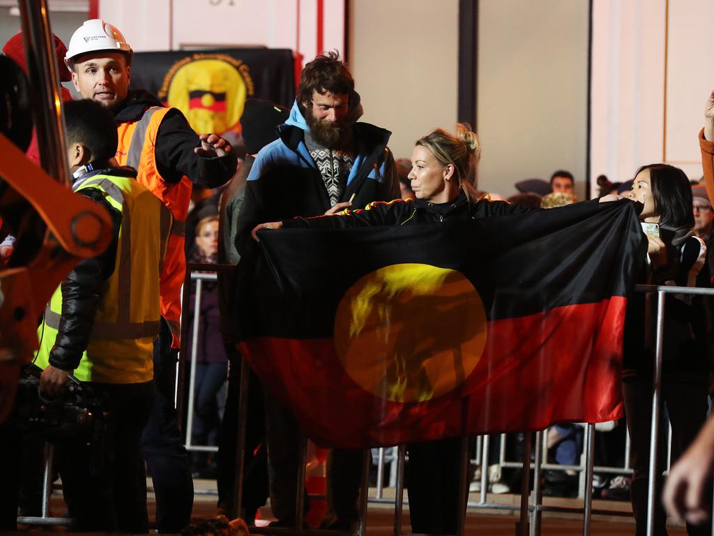 Dark Mofo 2018. Nala Mansell holds the Indigenous flag. Performance artist Mike Parr enters the chamber he will live in for 72 hours under Macquarie Street Hobart. Picture: NIKKI DAVIS-JONES