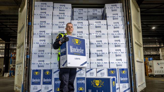 Australian Border Force officer Jake stands in front of a shipping container full of illegally imported cigarettes. Picture: Jake Nowakowski