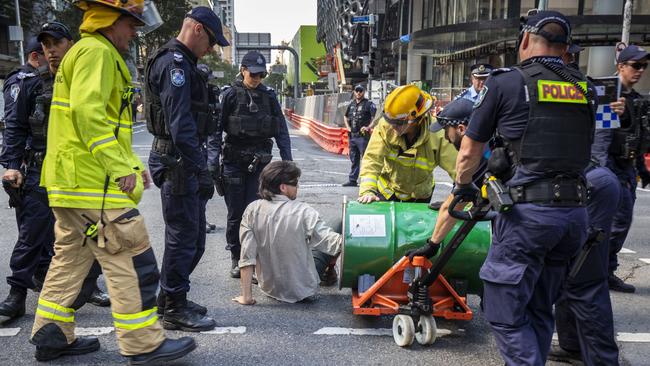 An activist from Extinction Rebellion with his arm in a barrel of concrete participating in a protest on George Street, Brisbane on Tuesday. Picture: AAP Image/Glenn Hunt