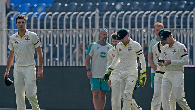 Australia's captain Pat Cummins (L) and teammates wear black armbands as they arrive to observe a minute silence and pay their respects Shane Warne. Picture: AFP