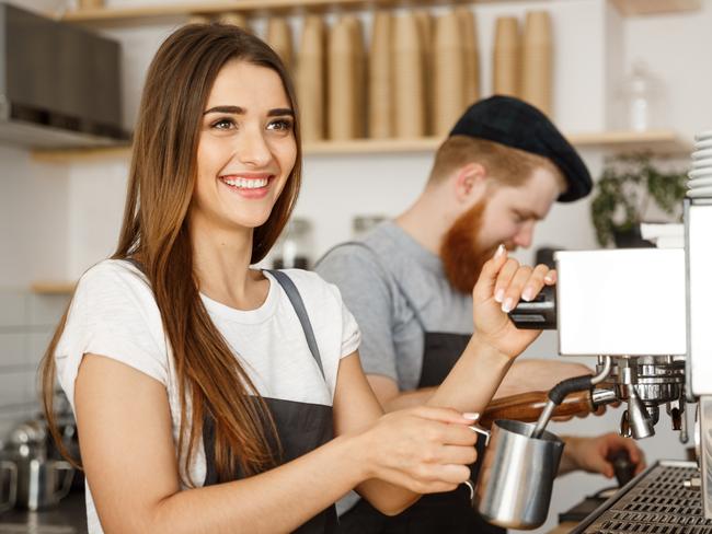 Coffee Business Concept - portrait of lady barista in apron preparing and steaming milk for coffee order with her partner while standing at cafe. Picture: iStock.