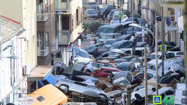 Pedestrians stand next to piled up cars in Sedavi, south of Valencia. Picture: Jose Jordan / AFP