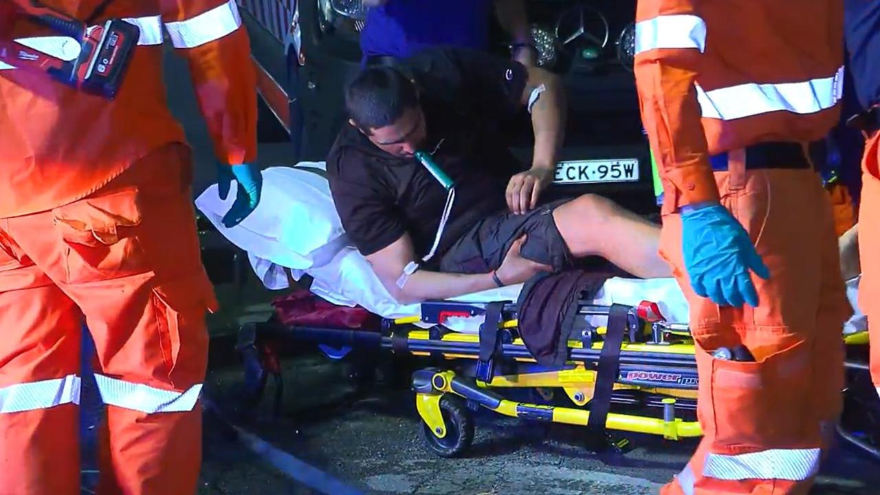 A man is treated by paramedics after a crash that happened in an exit lane from the Pacific Highway at Moonee Beach on March 9, 2022.