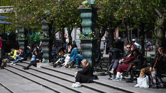 People enjoy the warm weather as they sit at Kungstradgarden in Stockholm. Picture: AFP