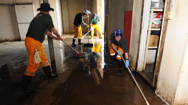 WASH DOWN: Volunteer fire fighters Terry Mooney and Kym Law wash down the interior of the Friendly Grocer in Queen Street North Bundaberg. Fire fighters from all over the region have been assisting in the flood recovery clean up. Photo: Mike Knott / NewsMail