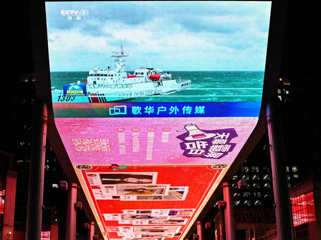 TOPSHOT - This picture shows a general view of a public big screen broadcasting news about China's military drills around Taiwan, outside a shopping mall in Beijing on April 1, 2025. China on April 1 sent its army, navy, air and rocket forces to surround Taiwan for large-scale drills Beijing said were aimed at practising for 