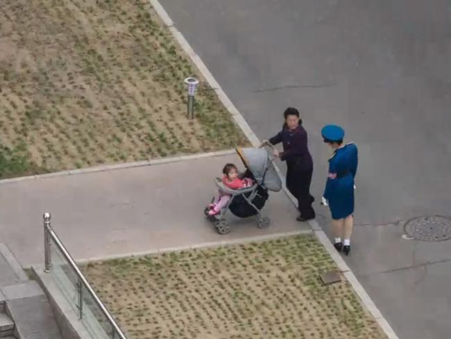 A traffic cop helps a woman pushing a pram in Pyongyang. Picture: Rob Whitworth and JT Singh/National Geographic