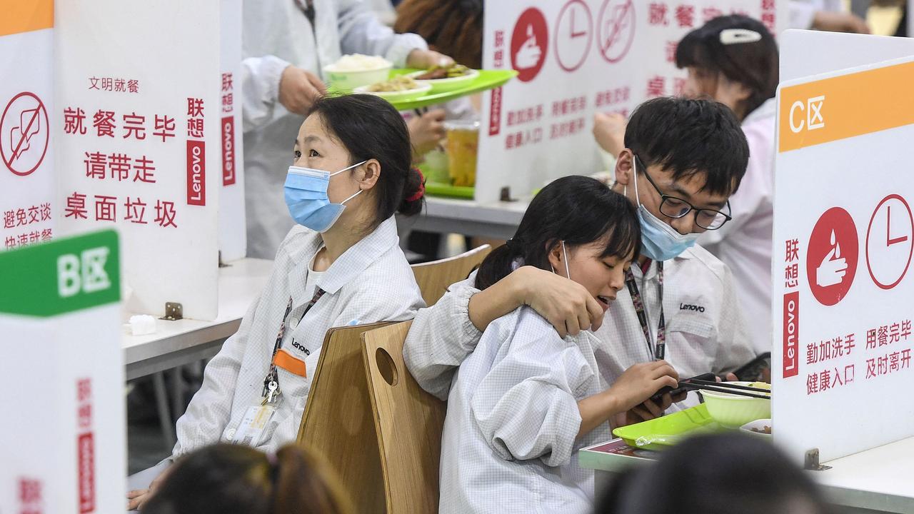 Lenovo factory employees eating at tables with plastic partitions in Wuhan, China’s central Hubei province. Picture: STR/AFP