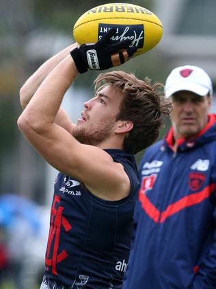 Jack Viney wears a glove to protects his knuckle as coach Paul Roos watches over training. Picture: Mark Dadswell