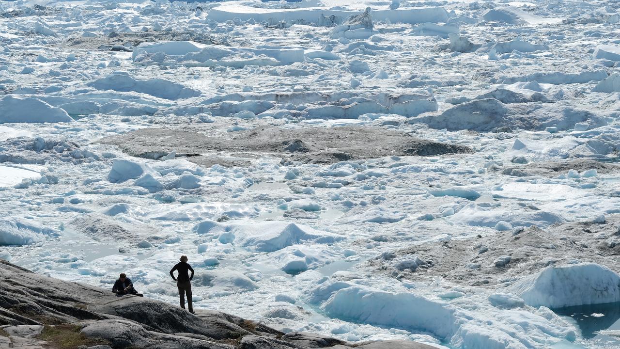 Visitors look out onto the free-floating ice jammed into the Ilulissat Icefjord during unseasonably warm weather. Picture: Sean Gallup/Getty Images