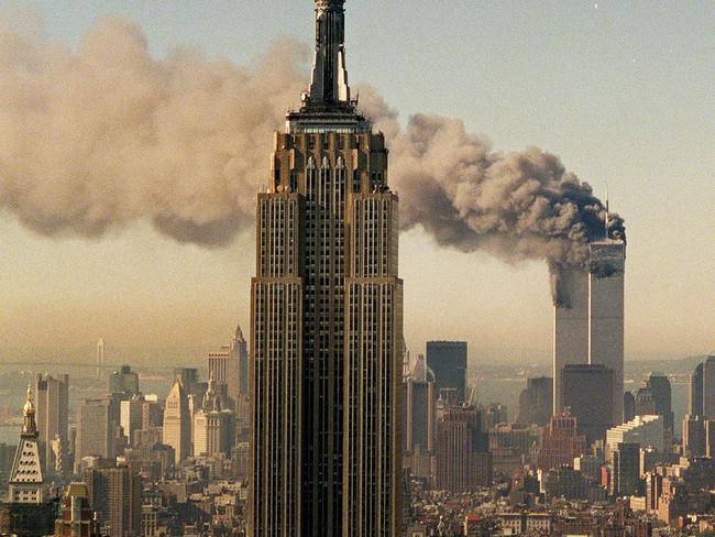 The twin towers of the World Trade Center burn behind the Empire State Building in 2001.