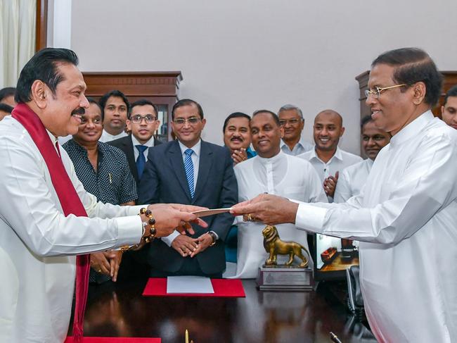 This handout released by Sri Lanka President media on October 26, 2018 shows former Sri Lankan president Mahinda Rajapakse (L) handing over documents to Sri Lankan President Maithripala Sirisena (R) as Rajapakse is sworn in as new Prime Minister, in Colombo. - President Maithripala Sirisena on October 26 sacked his Prime Minister Ranil Wickremesinghe and appointed former president Mahinda Rajapakse as the new premier, the president's office said. (Photo by Handout / Sri Lanka President Media / AFP) / -----EDITORS NOTE --- RESTRICTED TO EDITORIAL USE - MANDATORY CREDIT "AFP PHOTO /Sri Lanka President media " - NO MARKETING - NO ADVERTISING CAMPAIGNS - DISTRIBUTED AS A SERVICE TO CLIENTS.