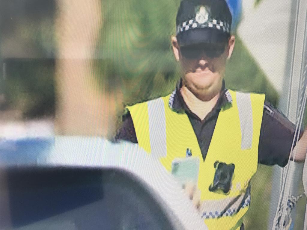 A driver passing through a checkpoint at Coolangatta while holding a mobile phone out the window to show their border declaration pass. Using a mobile phone while driving usually attracts a $1000 fine and the loss of four demerit points. Picture: Channel 7