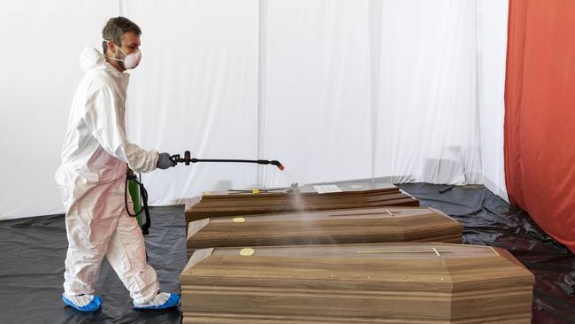 A Civil Protection staffer sanitises the coffin of a victim of COVID-19 in the hangar where 18 coffins wait to be transported to Florence by the Italian Army. Picture: Getty