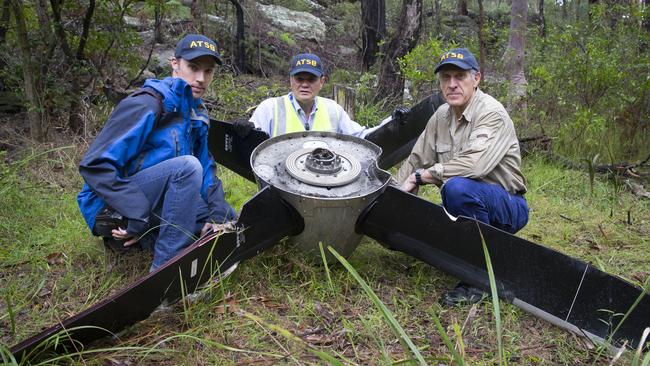 Australian Transport Safety Bureau investigators Aaron Holman (l to r), Greg Hood and Max Martin inspect the propeller that fell off a REX plane. Picture: Melvyn Knipe