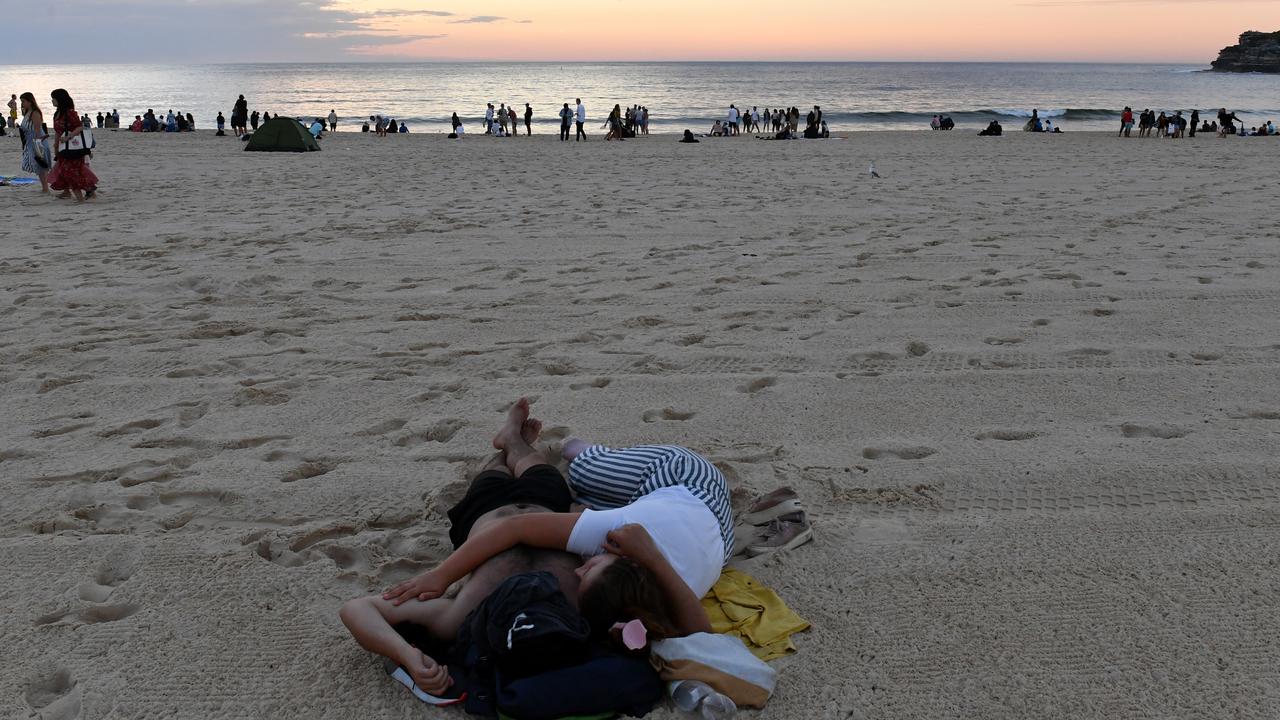 Revellers snuggle on the sand in the early hours of today. Picture: AAP 