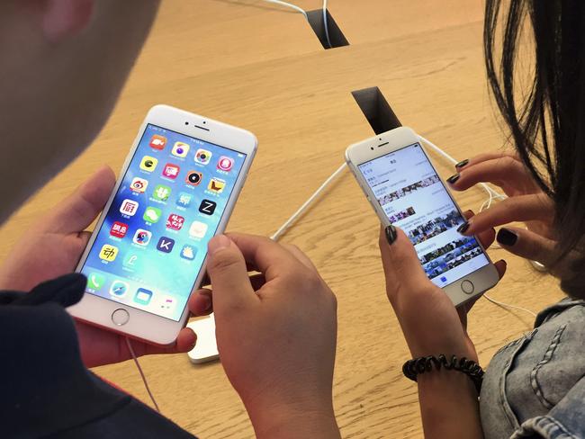 Customers try out Apple iPhone 6S models on display at an Apple Store in Beijing, Saturday, June 18, 2016. A Chinese regulator has ordered Apple Inc. to stop selling two versions of its iPhone 6 in the city of Beijing after finding it looks too much like a competitor, but Apple says sales are going ahead while it appeals. (AP Photo/Mark Schiefelbein)