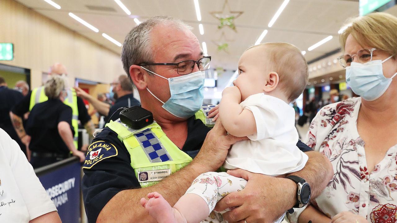 Tasmania Police Senior Constable Paul Edwards who was working at the airport on day 1 of border reopening reunited with granddaughter Isla, 7 months, from Newcastle who have been separated since she was 4 weeks old. Mum Lauren Edwards and grandmother Debbie Edwards look on. Picture: Nikki Davis-Jones