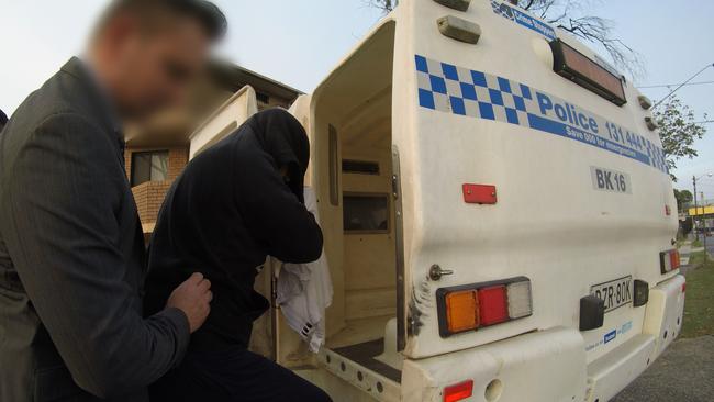 Detectives lead the man to a police car after searching a Yagoona home. Picture: NSW Police