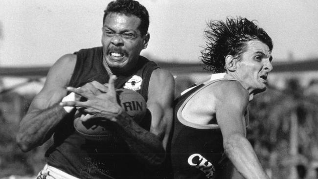 St Mary's Dennis Dunn grabs the ball before Darwin's David Atkinson can punch it out of his reach during an NTFL match held at the Gardens Oval in 1994.