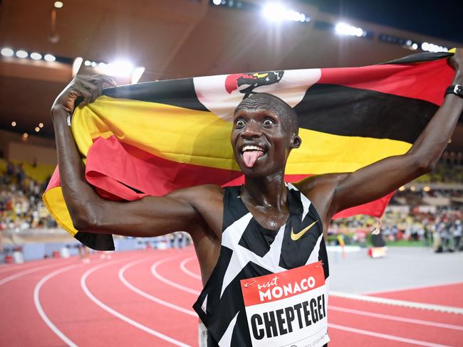 Uganda's Joshua Cheptegei waves an Uganda national flag as he celebrates after winning and breaking the world record in the men's 5000metre event during the Diamond League Athletics Meeting at The Louis II Stadium in Monaco on August 14, 2020. (Photo by Matthias Hangst / various sources / AFP)