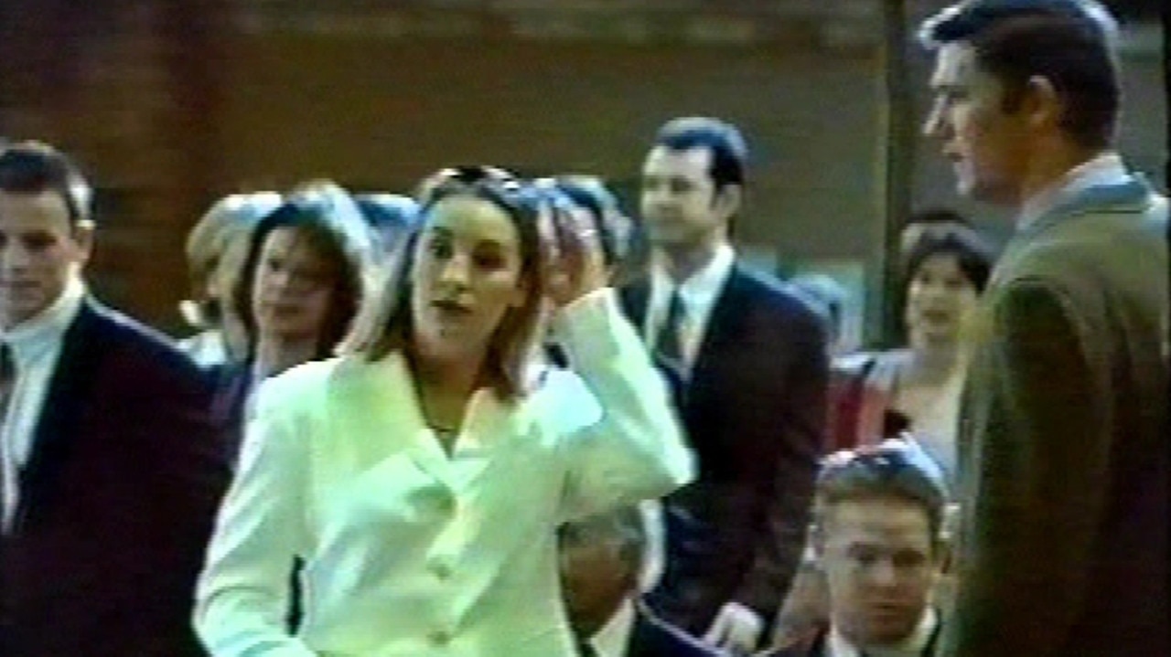 Video still of Lane (white coat) with then boyfriend Duncan Gillies (far right) at a friend’s 1996 wedding hours after killing her two day-old baby.