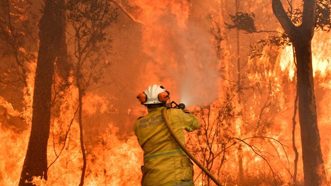 This file photo taken on December 10, 2019 shows a firefighter conducting backburning measures to secure residential areas from encroaching bushfires in the Central Coast, some 90-110 kilometres north of Sydney. – Climate change is already buffeting Australia with more extreme bushfires, droughts and cyclones — and the fossil-fuel reliant country should brace for worse to come, according to Australia's top science and weather agencies on November 13, 2020. (Photo by Saeed KHAN / AFP)