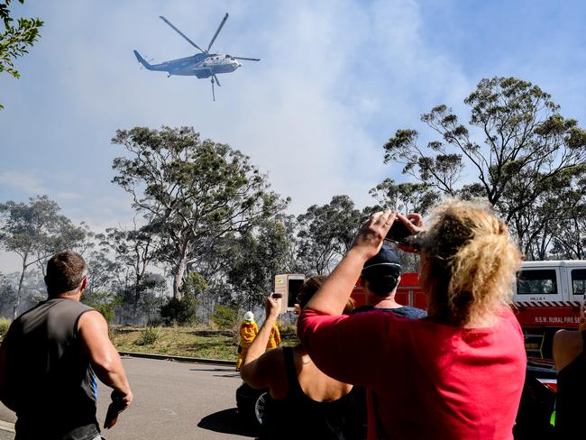 Residents look on as fire bombing is used to control spot fires in Gandangara Estate Barden Ridge. Picture: Brendan Esposito