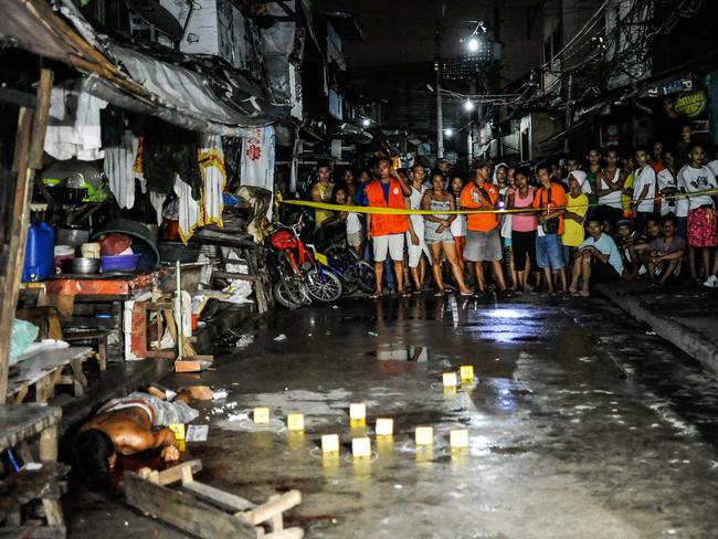 Police examine the body of an alleged drug dealer at a Manila market. Picture: Getty Images