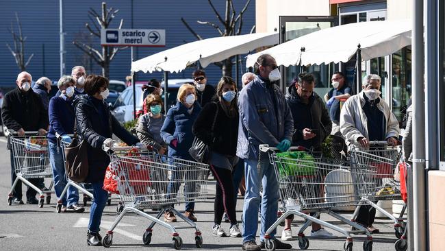 Residents wearing masks wait to do their shopping outside a supermarket in Codogno, southeast of Milan, in March. Picture: AFP