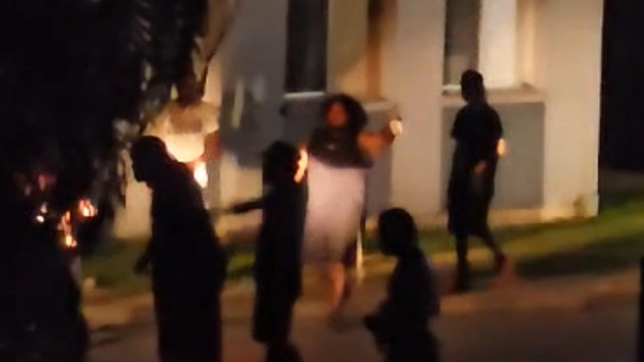 Drinks in hand, a group of men block a vehicle from heading home.