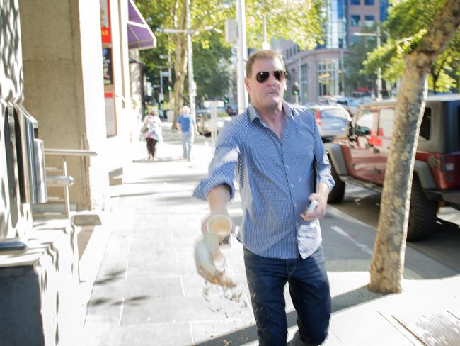 Ricky Nixon throws a coffee at a <i>Herald Sun</i> photographer while entering a VCAT hearing. Picture: Eugene Hyland