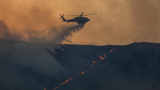 A firefighting helicopter drops water over the Hughes fire in Castaic. Picture: AFP