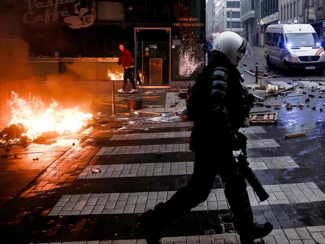 A Belgian riot policeman runs past a fire. Picture: AFP