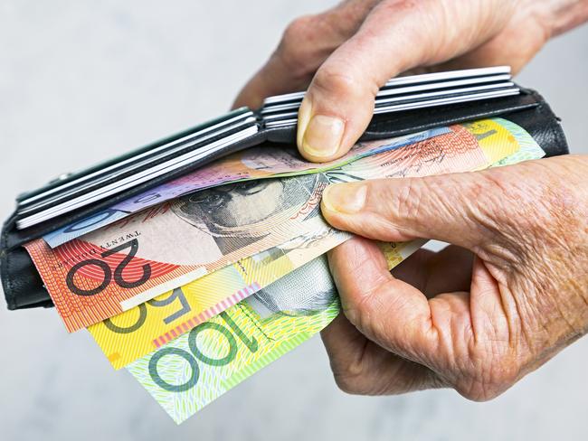 Close-up, senior female hands taking Australian banknotes (cash, currency) from purse containing many credit cards.  Horizontal, studio, copy space. Money generic