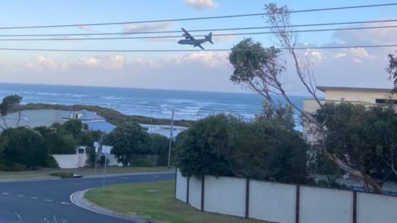 A RAAF plane flying low over houses and the coastline at Ocean Grove.