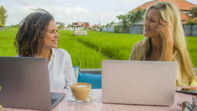 two happy female friends working outdoors at beautiful internet cafe with laptop computer , a caucasian woman and an afro mixed ethnicity girl enjoying together as digital nomad girlfriends. Drinking coffee, Digital Nomad, Freelancer, Bali, Picture - Istock